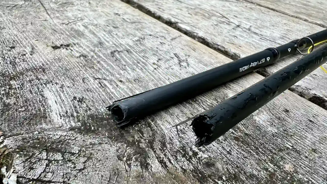 Broken sections of a black Nam Delgado fly rod on weathered wood.